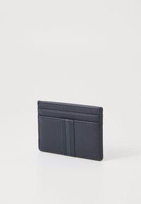 Navy cardholder made of smooth leather with three slots, featuring two vertical texture stripes and subtle stitching detail.
