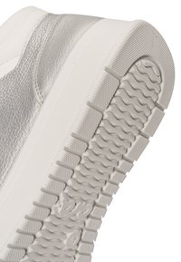 Schuhsohle aus weißem Gummi mit strukturiertem Griffmuster, metallisch silbernes Obermaterial mit genähter Lederstruktur und dicke weiße Zwischensohle.