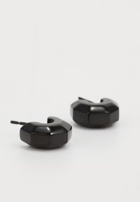 Musthave kuusnurkse kujuga kõrvaklapid, mis on valmistatud läikivast plastikust. Omavad geomeetrilist disaini ja kinnitust, mis tagab kindla kandmise.