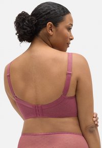 Sujetador en tela malva con un patrón texturizado. Cuenta con tirantes ajustables y un cierre de gancho y ojal en la parte posterior. Acabado suave y liso.