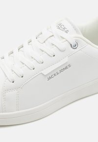 Vita lädersneakers med platta vita skosnören, rund tå och texturerad vit gummisula. Har "JACK&JONES"-logotypen på sidan.
