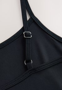 Schwarzes sportliches Tanktop mit dünnen Trägern, verstellbarer Metallhardware, glattem Jersey-Stoff und kontrastierenden Steppnähten.