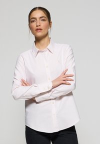 Camicia a righe rosa chiaro con bottoni, realizzata in cotone, con colletto, maniche lunghe e un piccolo logo ricamato sul lato sinistro del petto.