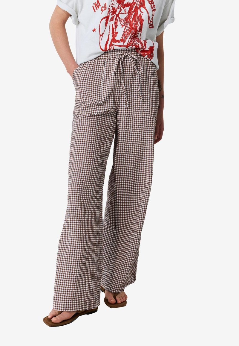 Rudos ir baltos spalvos languoti plačios kelnės su raištelių juosmeniu ir lengva medžiaga. Turi šonines kišenes ir laisvą siluetą.