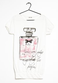 Camiseta blanca con un gran gráfico de un frasco de perfume en gris y rosa, que presenta un lazo negro y el texto "Se puede juzgar a una chica por su perfume."