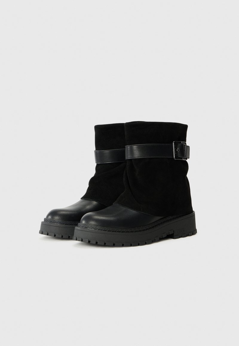 Schwarze Stiefeletten mit einem Obermaterial aus Wildleder, Gummisohle und einem glatten Lederbesatz mit einer Schnalle am Knöchel.