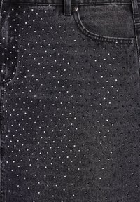 Tissu en denim noir présentant un motif à pois de petites clous métalliques répartis uniformément sur la surface. Design classique à cinq poches.