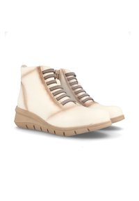 Botas de tobillo de color beige claro con un acabado de cuero suave, que presentan cordones laterales texturizados y una suela de goma. Cierre de cremallera en un lado.