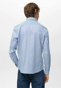 Camicia a maniche lunghe a righe blu e bianche con collo a risvolto, design con bottoni davanti e orlo curvo. Il materiale sembra liscio e leggero.