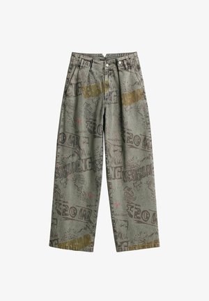 Pantalones vaqueros verdes de corte ancho. Presentan varias gráficas y textos en colores contrastantes, con un acabado de tela texturizada.