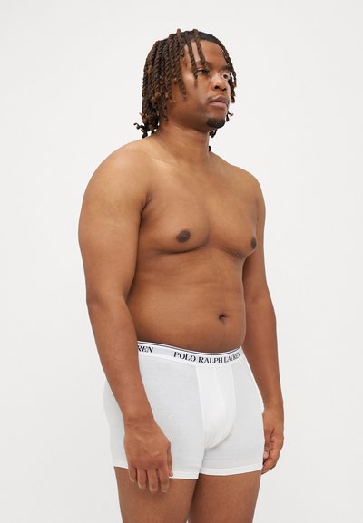 Fehér pamut boxer alsónadrág fekete derékpánttal, amelyen fehér betűkkel szerepel a "POLO RALPH LAUREN" felirat, oldalnézetből bemutatva férfi modellen.