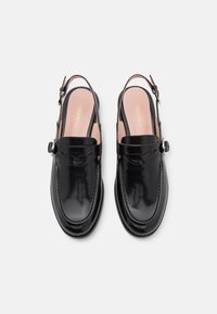 Black patent leather slingback shoes with a rounded toe, decorative stitching, and a small buckle on the adjustable strap.