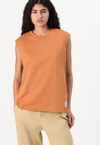 T-shirt sans manches orange avec col rond, texture douce et fentes sur les côtés. Une petite étiquette avec logo est visible au bas de l'ourlet.