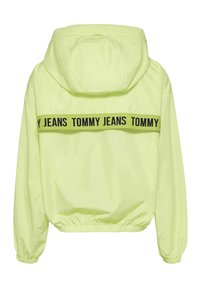 Neongul vindjacka med huva, elastiska ärmslut och dragsko i nederkant. Har ett svart "TOMMY JEANS" logoband på baksidan.