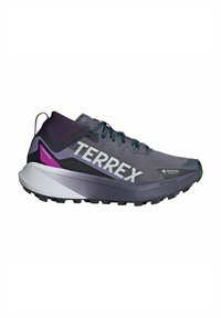 Scarpe da corsa grigie e viola con una tomaia testurizzata, il logo "TERREX" ben visibile e una suola multicolore progettata per offrire trazione.