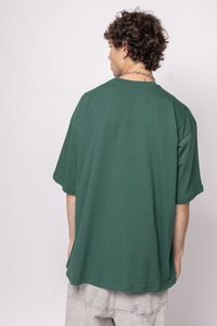 Green oversized t-shirt made of cotton, featuring a round neckline and short sleeves. The material has a smooth texture.
