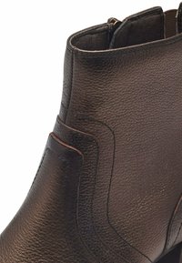 Braunes Lederknöchelboot mit strukturiertem Finish, ausgestattet mit einem seitlichen Reißverschluss und kontrastierenden Nähten. Abgerundete Zehenpartie und schlanke Form.