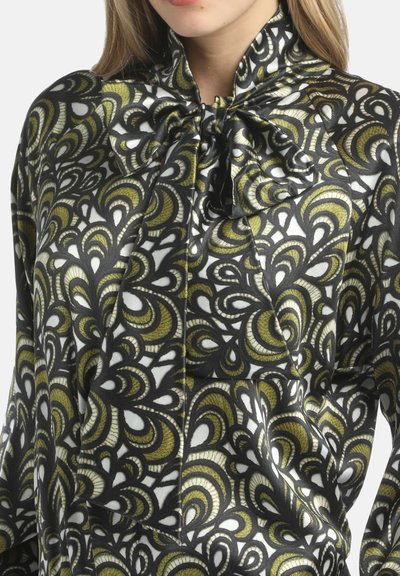 Blusa bianca e nera con un motivo astratto verde e oro, in materiale satinato, colletto alto con dettaglio a fiocco e maniche lunghe.