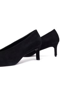 Chaussures à talons hauts en daim noir avec un bout pointu et un talon fin. La surface présente une texture lisse et des lignes de design épurées.