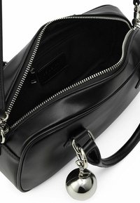 Schwarze Ledertasche mit silberner Beschlägen, Reißverschluss und einem runden Anhänger. Das Innere verfügt über ein Etikett und eine zusätzliche Reißverschlusstasche.