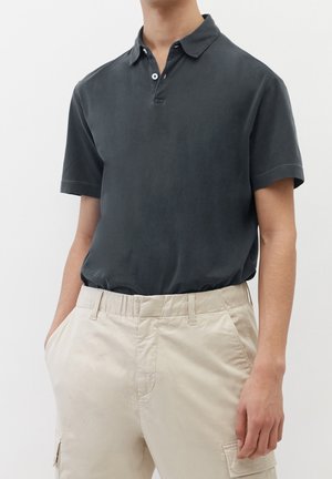 Polo-shirt court gris foncé à manches courtes avec un col, patte de boutonnage à deux boutons, texture douce, associé à un pantalon cargo beige avec poches latérales.