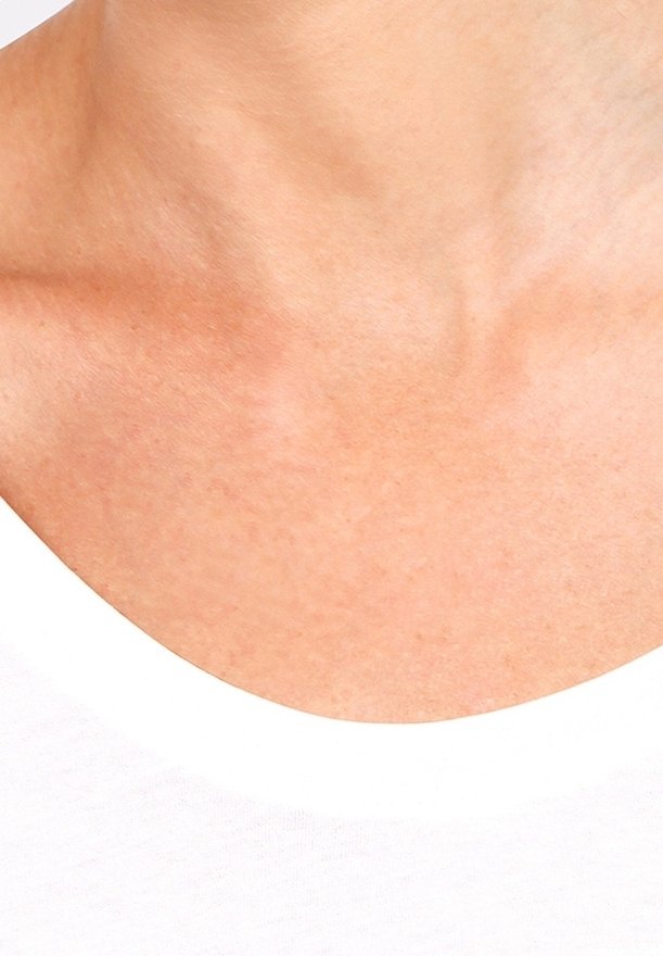 Gros plan sur le cou propre et nu ainsi que sur le haut de la poitrine d'une personne portant un col de chemise blanc.