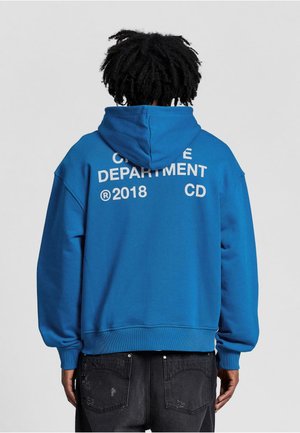 Blue hoodie with a large white graphic on the back, featuring text "CREATIVE DEPARTMENT 2018 CD". Loose fit, soft texture, and kangaroo pocket.