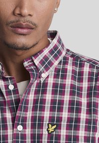 Camicia a scacchi in tonalità di rosa, blu navy e bianco. Presenta un colletto button-down e un piccolo logo ricamato sulla tasca del petto.