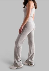 Szary prążkowany top bez rękawów i dopasowane spodnie w kształcie dzwonów wykonane z miękkiego materiału. Strój charakteryzuje się dopasowanym krojem i gładką fakturą, dopełniony białymi trampkami.