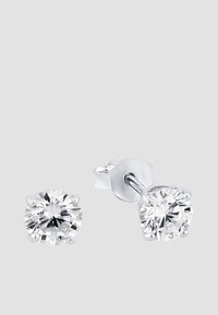 Runda studs med klara, glittrande stenar i silvrig metall med en minimalistisk design. Varje örhänge har fyra klor.