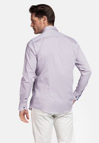 Chemise à manches longues de couleur violet clair avec un petit motif géométrique. Dotée d'un col pointu et de boutons contrastants sur les poignets.