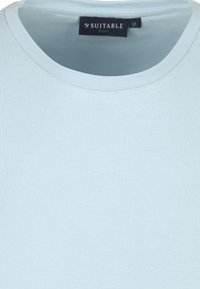 Lichtblauw rundekraag t-shirt gemaakt van zachte, gladde katoen; bevat een label met "SUITABLE" en maat M zichtbaar aan de hals.
