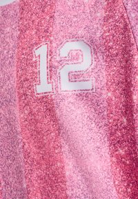 Nummer 12 in witte blokletters met omlijning op een gestructureerde achtergrond van roze en rode strepen stof.