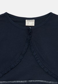 Μπλε βαμβακερό T-shirt ναυτικού χρώματος με φρουφρού στη λαιμόκοψη, κούμπωμα με κουμπιά και λεία, υφασμένη γάζα. Η ετικέτα μεγέθους υποδεικνύει ηλικία 8 ετών.