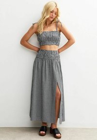 Black and white gingham crop top with adjustable straps, paired with a matching ankle-length skirt featuring a side slit and smocked waistband.