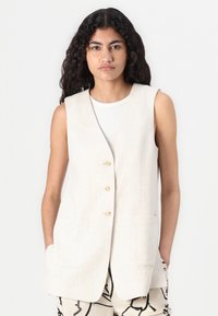 Beige linen vest with a v-neck design, three front buttons, and two side pockets, displaying a textured fabric and a relaxed fit.