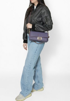 Paarse handtas met textuur, voorzien van een kettinghengsel en gouden hardware. Draag het met een zwarte bomberjack en lichtblauwe wide-leg jeans.