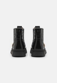 Botine din piele veritabilă neagră, cu un finisaj neted, vârf rotund, accente texturate și o talpă din cauciuc masivă. Include o bandă de prindere pentru a fi ușor de purtat.