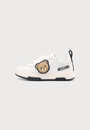 Baskets blanches avec semelle noire, avec un visage d'ours brun sur la sangle et le logo "Moschino" sur le côté et la languette du talon.