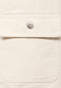 Witte canvas stof met een grote voorzak, voorzien van een zilveren drukknop en zichtbare stiksels rondom de randen.