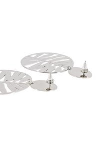 Orecchini in metallo argento con dischi circolari e motivi a foglia intagliati, dotati di perni. Texture liscia con una finitura lucida.
