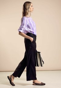 Camicia a righe viola e bianche, pantaloni neri a gamba larga, scarpe slip-on nere in rete e borsa a tracolla a righe bianco e nera. Texture liscia.