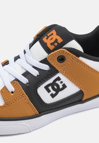 Tenisky s čiernym, bielym a oranžovým koženým zvrškom so štruktúrovaným povrchom, bielymi šnúrkami a logom na jazyku.