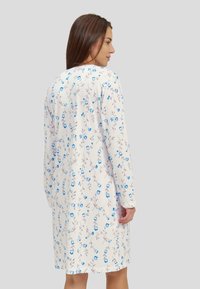 Camisón floral en tejido ligero, con una base blanca y patrones de flores azules, mangas largas y un diseño hasta la rodilla.