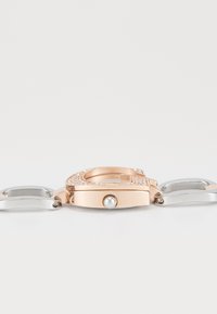 Ceas de brățară cu ton roz aurit și argintiu, cu carcasă rotundă, accente decorative din cristale și un detaliu din perlă pe închizătoare.