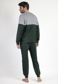 Conjunto de ropa de estar en casa para hombre que incluye una parte superior gris con la parte inferior en verde oscuro y pantalones verdes a juego. Tejido suave, corte relajado, puños elásticos.