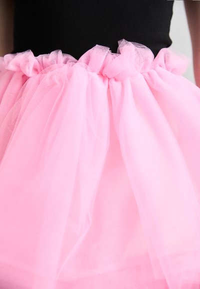Roze tule rok met gathering in de taille, met een zachte, doorschijnende textuur. De top is zwart, wat contrasteert met de lichtroze stof.