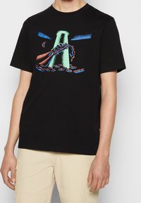 Svart bomullströja med en färgglad grafik av en bil som blir transporterad av ett UFO, med moln och månaksenter. Korta ärmar.