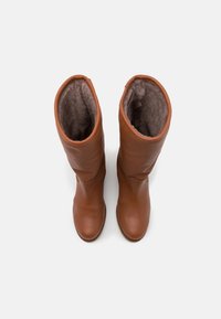 Bottes marron en cuir montant jusqu'aux genoux avec une finition lisse, une doublure intérieure douce et des bouts arrondis. Le design comporte un bord supérieur retroussé.