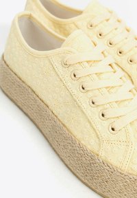 Gelbe Leinen-Sneaker mit geprägtem floralen Muster, runder Schnürdesign und strukturierter beigefarbener Espadrille-Sohle.